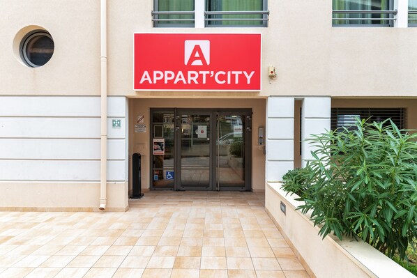 La entrada a un edificio de apartamentos con un letrero rojo que dice "APPART'CITY".