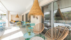 An outdoor seating area with wicker chairs, tables, and hanging lamps. - Appart'City Confort La Ciotat Cote Port (La Ciotat)