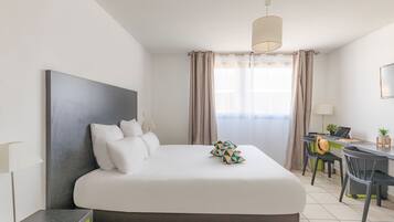 A modern hotel room with a large bed, a desk, and a chair.