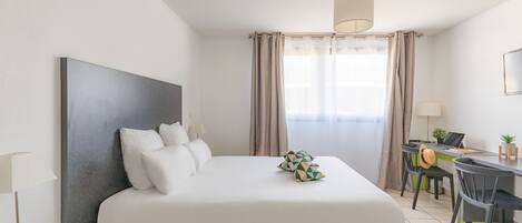A modern hotel room with a large bed, a desk, and a chair.