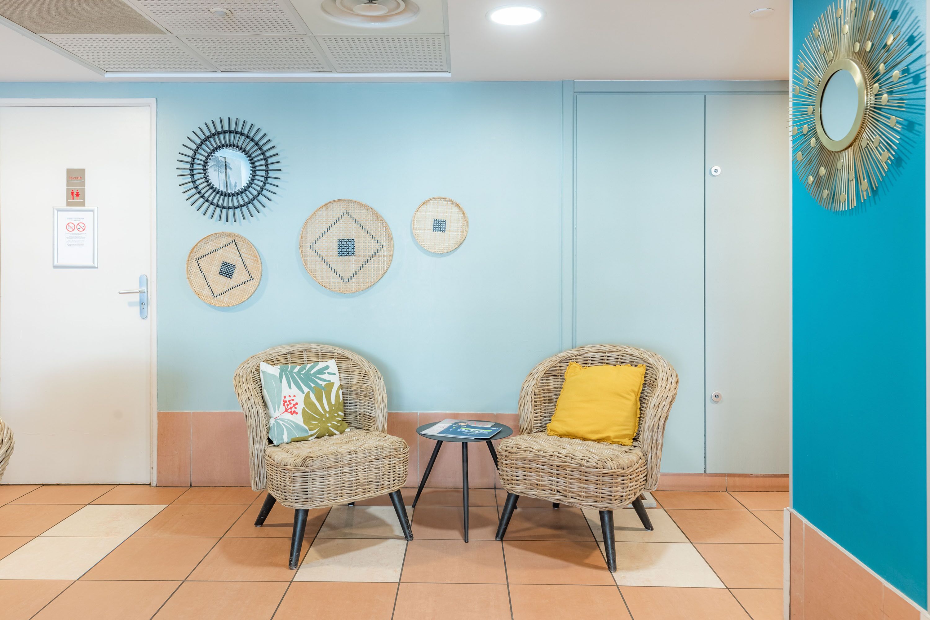 A room with two wicker chairs, a small table, and decorative wall art.