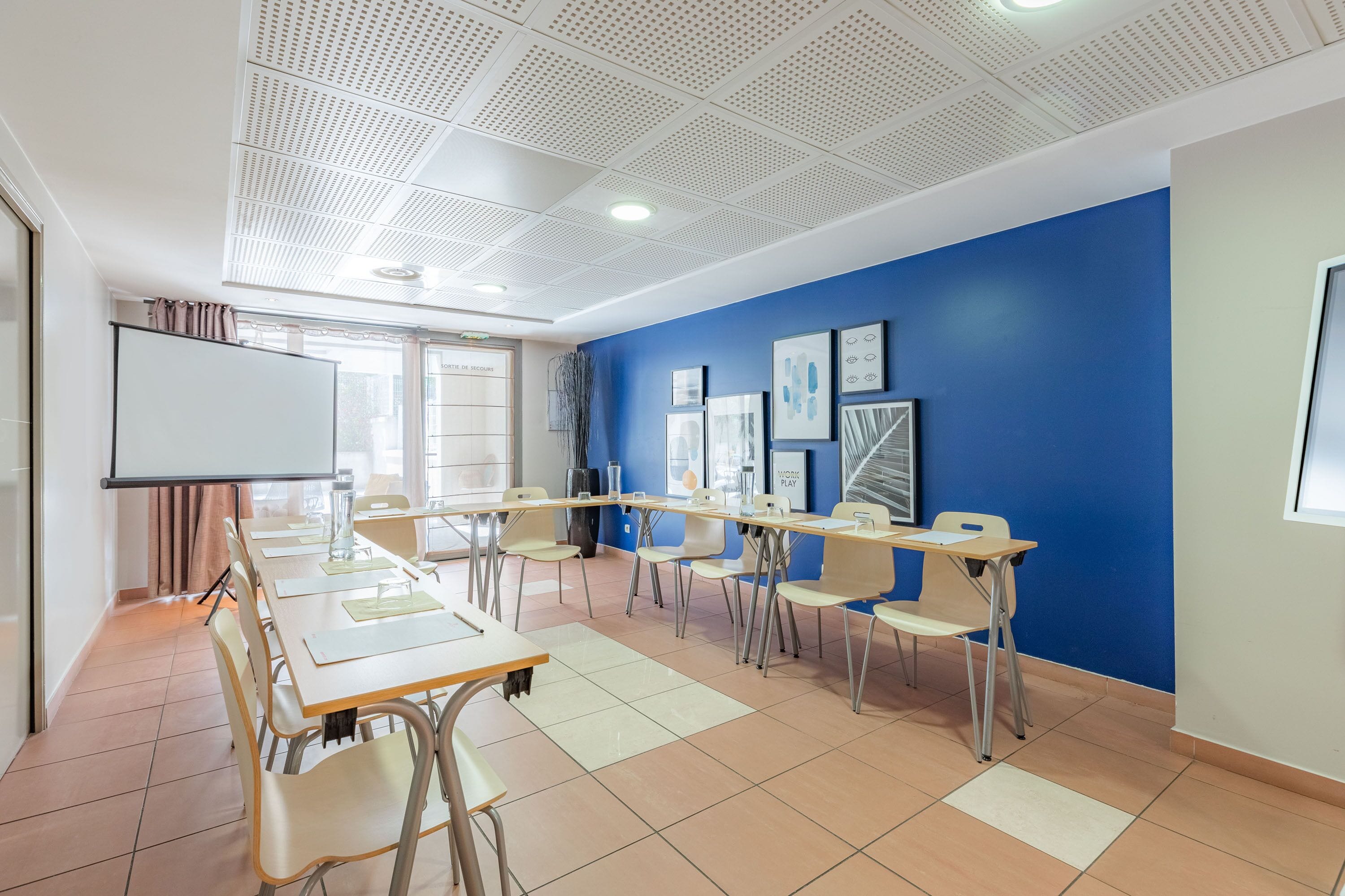 A classroom with a whiteboard, tables, and chairs arranged for a meeting.