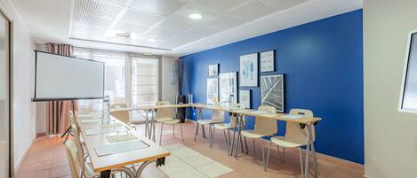 A classroom with a whiteboard, tables, and chairs arranged for a meeting.