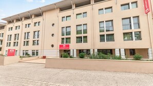 A multi-story building with a beige facade, multiple windows, and a red sign indicating an apartment complex. - Appart'City Confort La Ciotat Cote Port (La Ciotat)