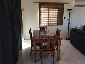 A dining area with a wooden table and chairs, a potted plant, and a floor lamp. - Airport Whyalla Motel (Whyalla Norrie)