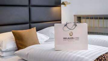 Una habitación de hotel con una cama, almohadas, un cabecero y una bolsa blanca con texto.