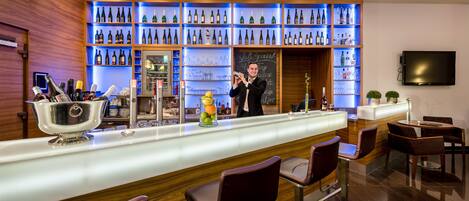 A bar area with a bartender, shelves of bottles, and bar stools.