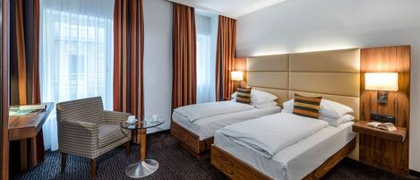 Una habitación de hotel con dos camas, un escritorio, una silla y una mesita.