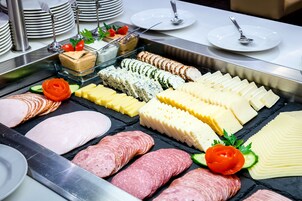 Buffet com diversos carnes, queijos e acompanhamentos.
