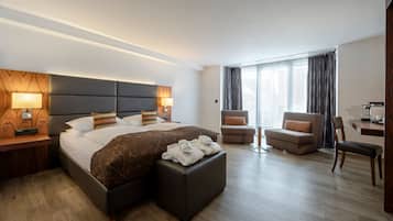 A modern hotel room with a large bed, a sofa, a chair, and a desk.