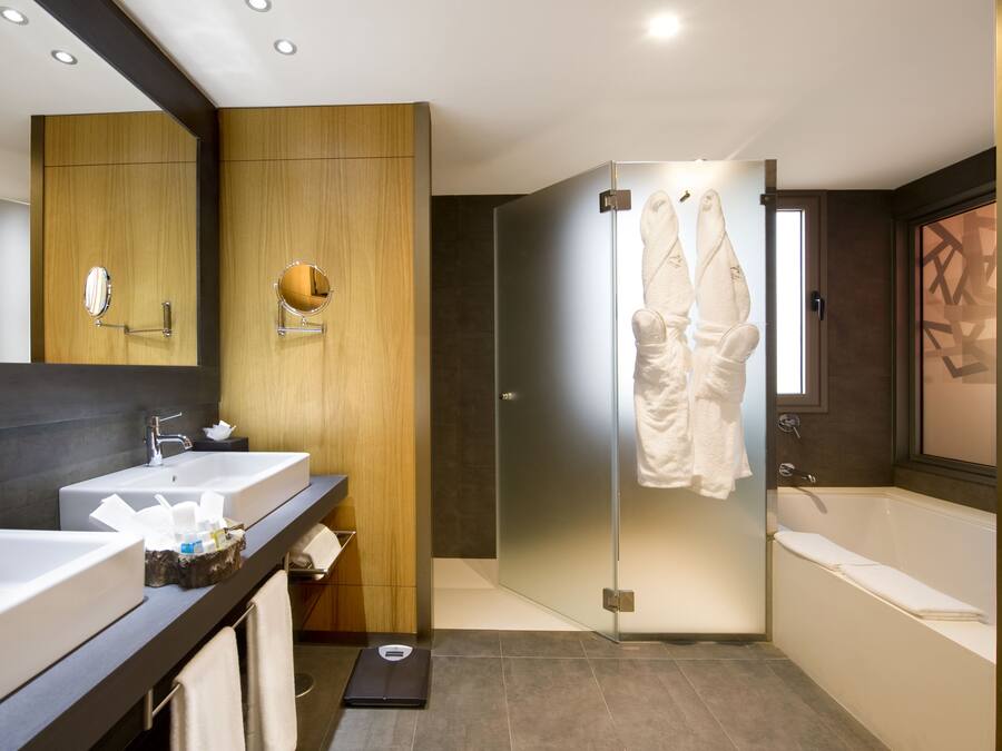 Un baño moderno con lavamanos dobles, un espejo grande y cabina de ducha de vidrio.