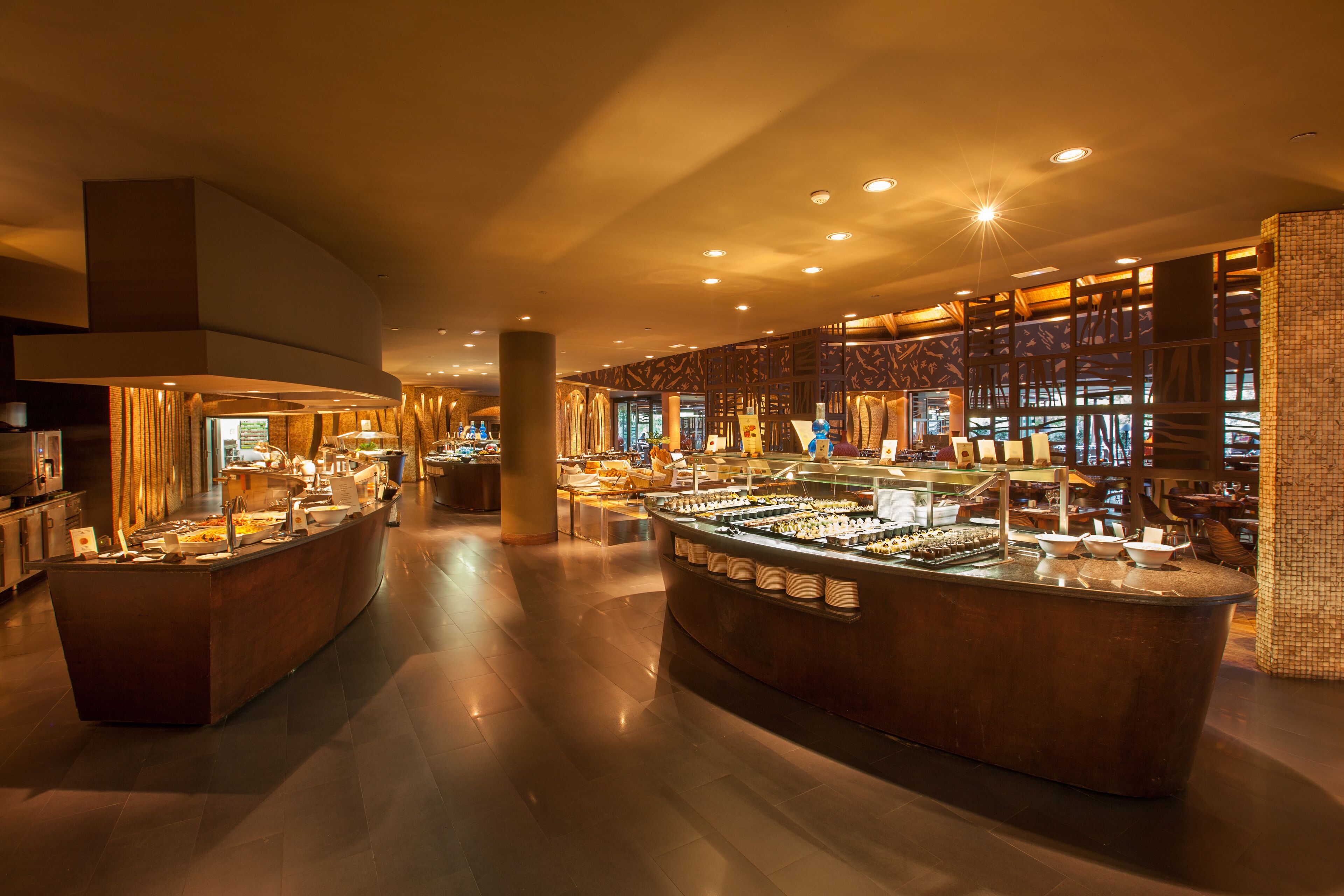 Um saguão de hotel moderno com uma área central de buffet, um pilar grande e um revestimento de parede estampado.
