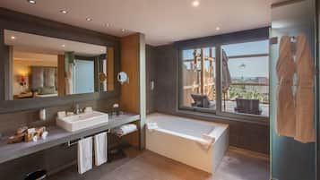 Une salle de bain moderne avec un grand miroir, deux lavabos, une baignoire et une fenêtre donnant sur un balcon et un avion.