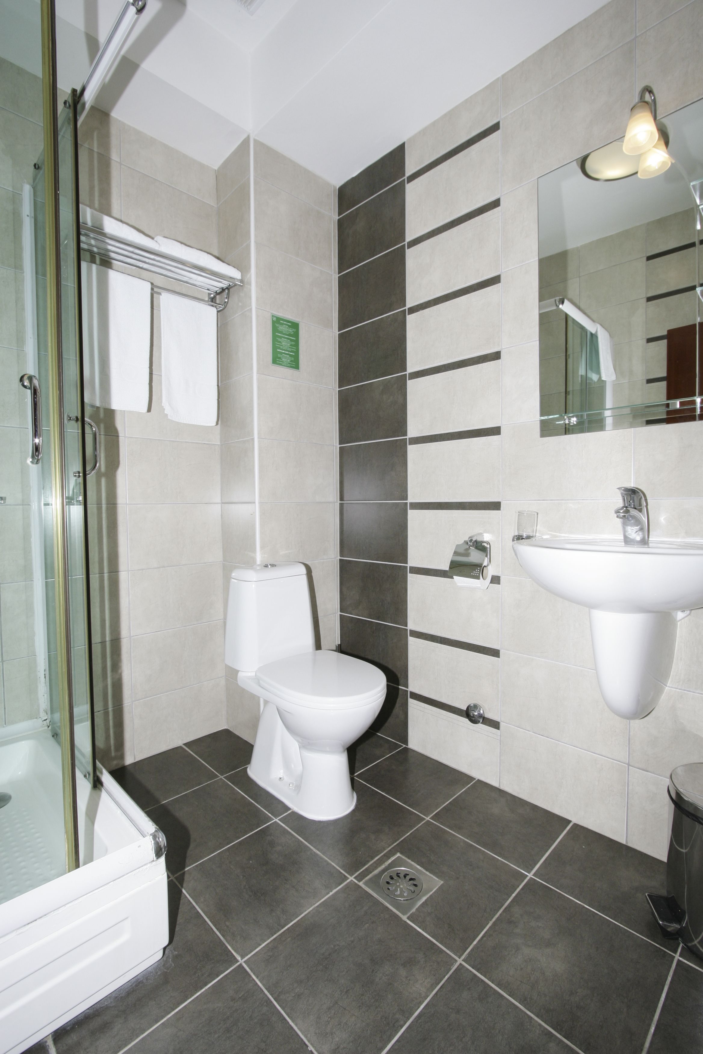 Ein modernes Badezimmer mit Duschkabine aus Glas, Toilette, Waschbecken und Spiegel.