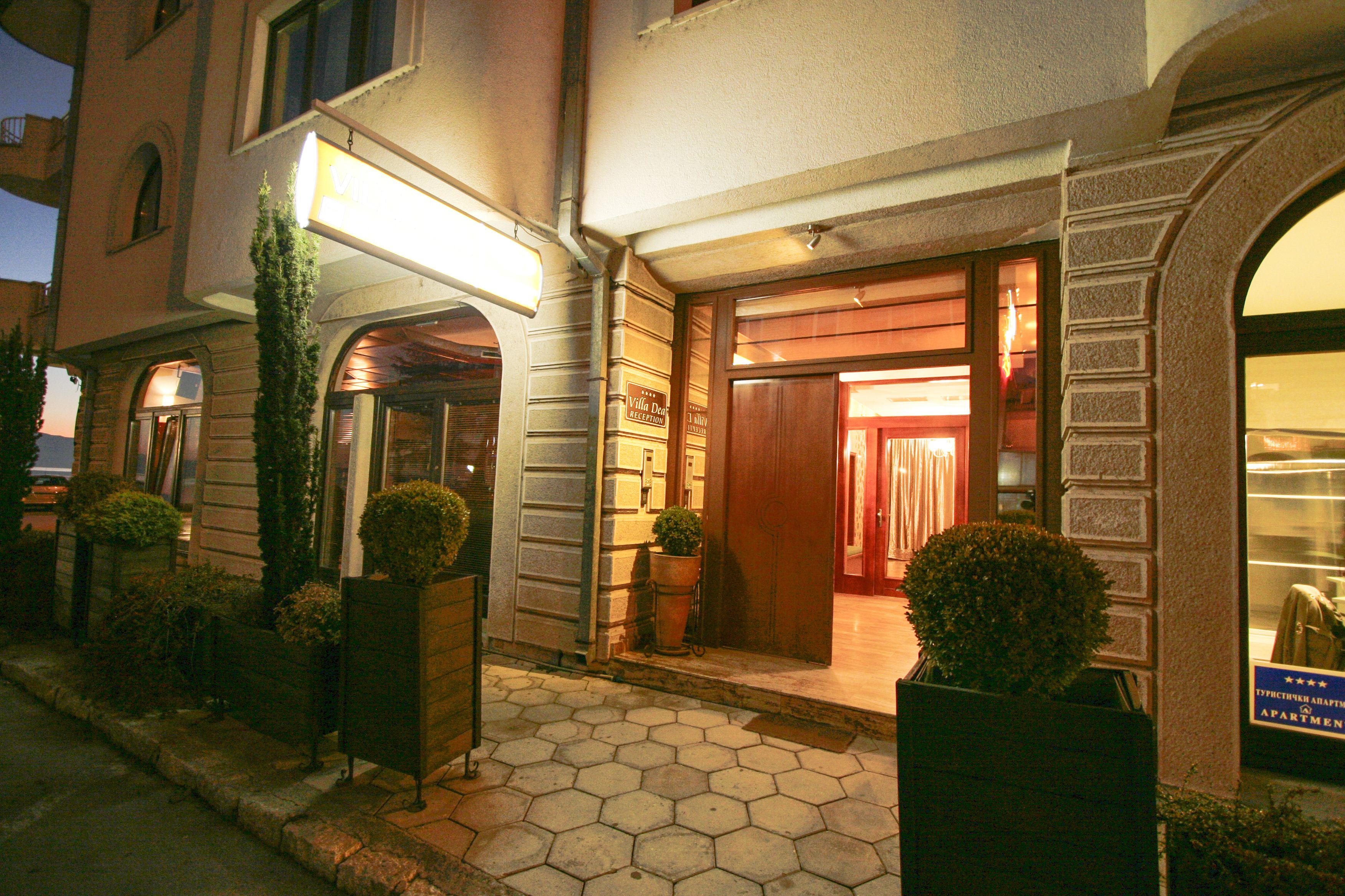 A hotel entrance with a wooden door, potted plants, and a sign indicating it is a hotel.
