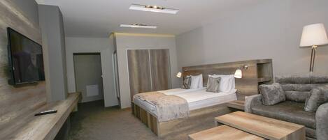 Una habitación de hotel moderna con cama, sofá, televisión y escritorio.
