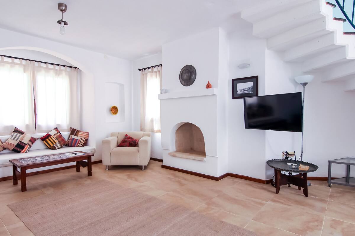 Una sala de estar moderna con sofá, mesa de centro, chimenea, televisor y escalera.