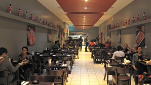 A restaurant with multiple tables and chairs, a tiled floor, and a red ceiling. - Brunswick Tower Hotel (Brunswick)