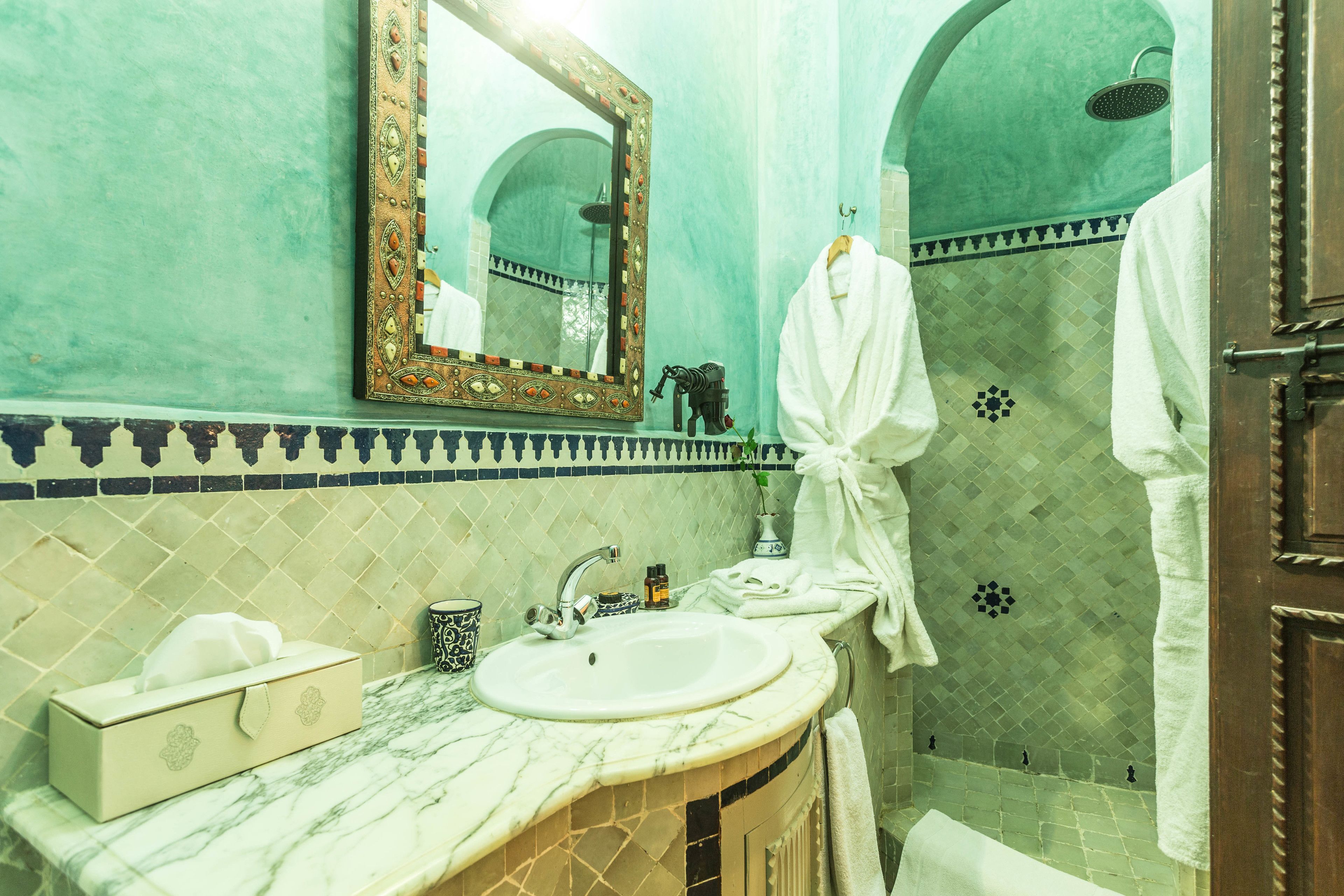 A bathroom with a sink, mirror, and shower.