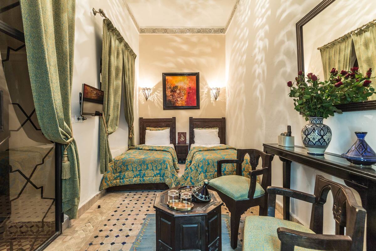 Quarto com duas camas, uma mesa com um vaso de flores e um espelho na parede.