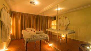 A spa room with a bed, a mirror, and a robe rack.