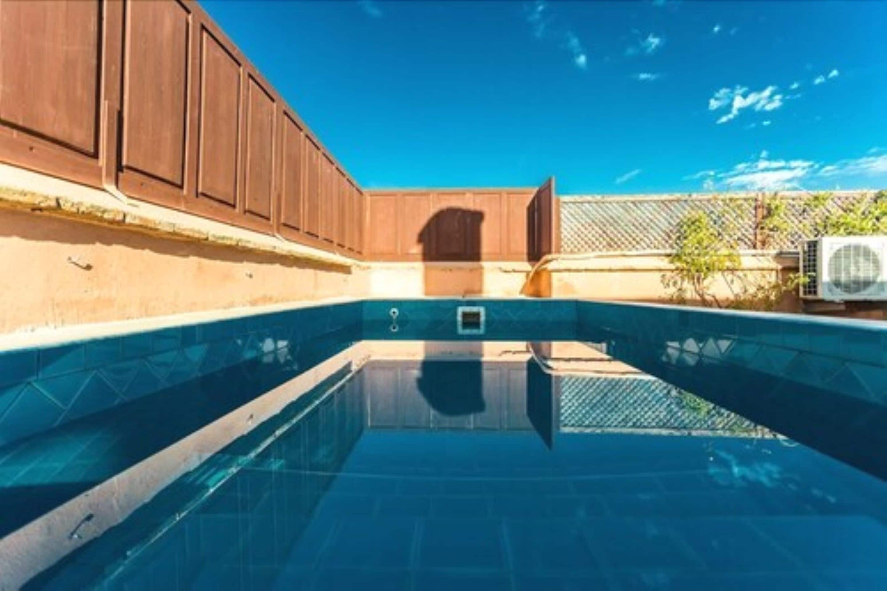 A swimming pool with a wooden deck and a clear blue sky.