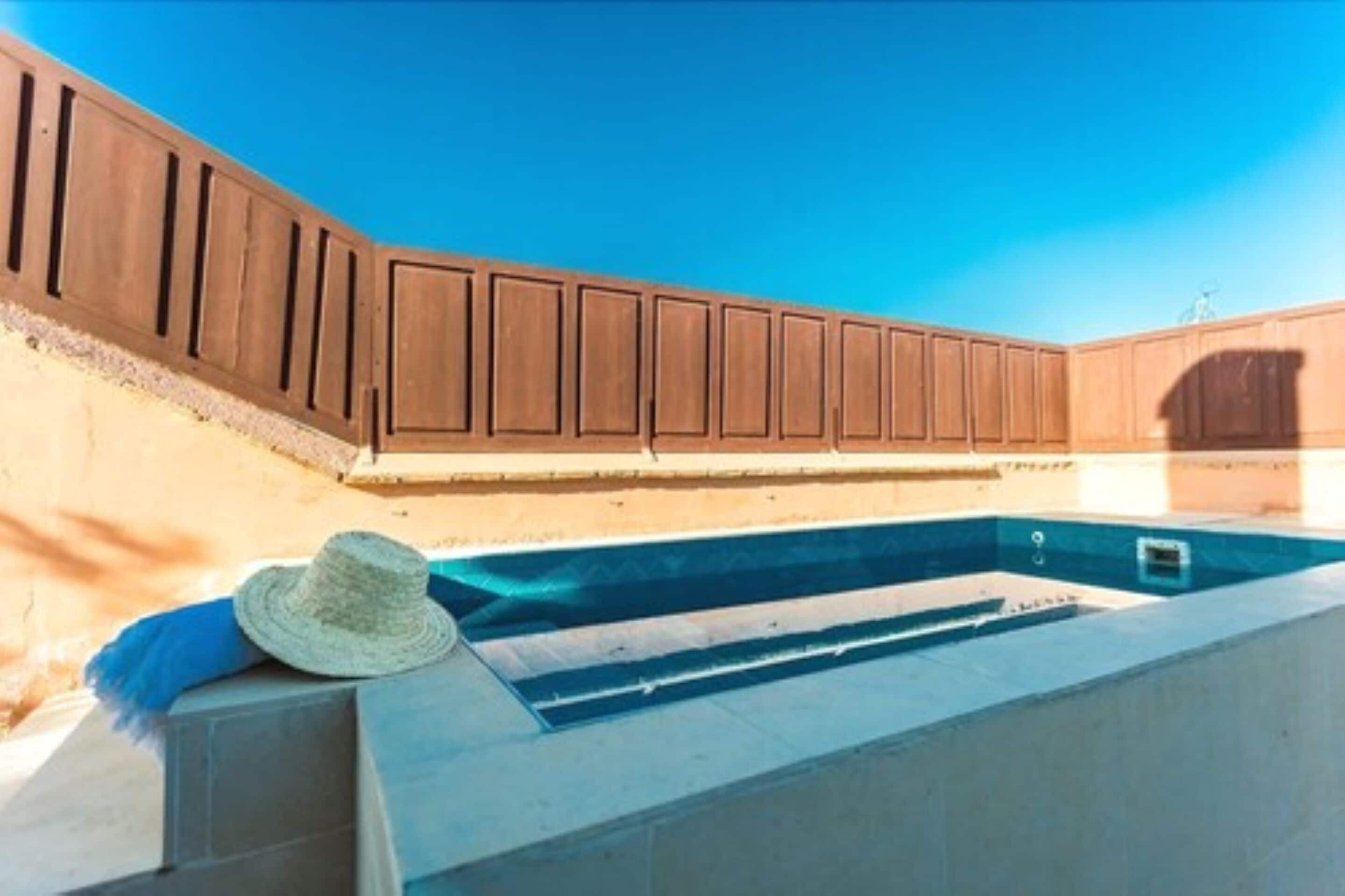 A swimming pool with a wooden deck and a hat on the edge.