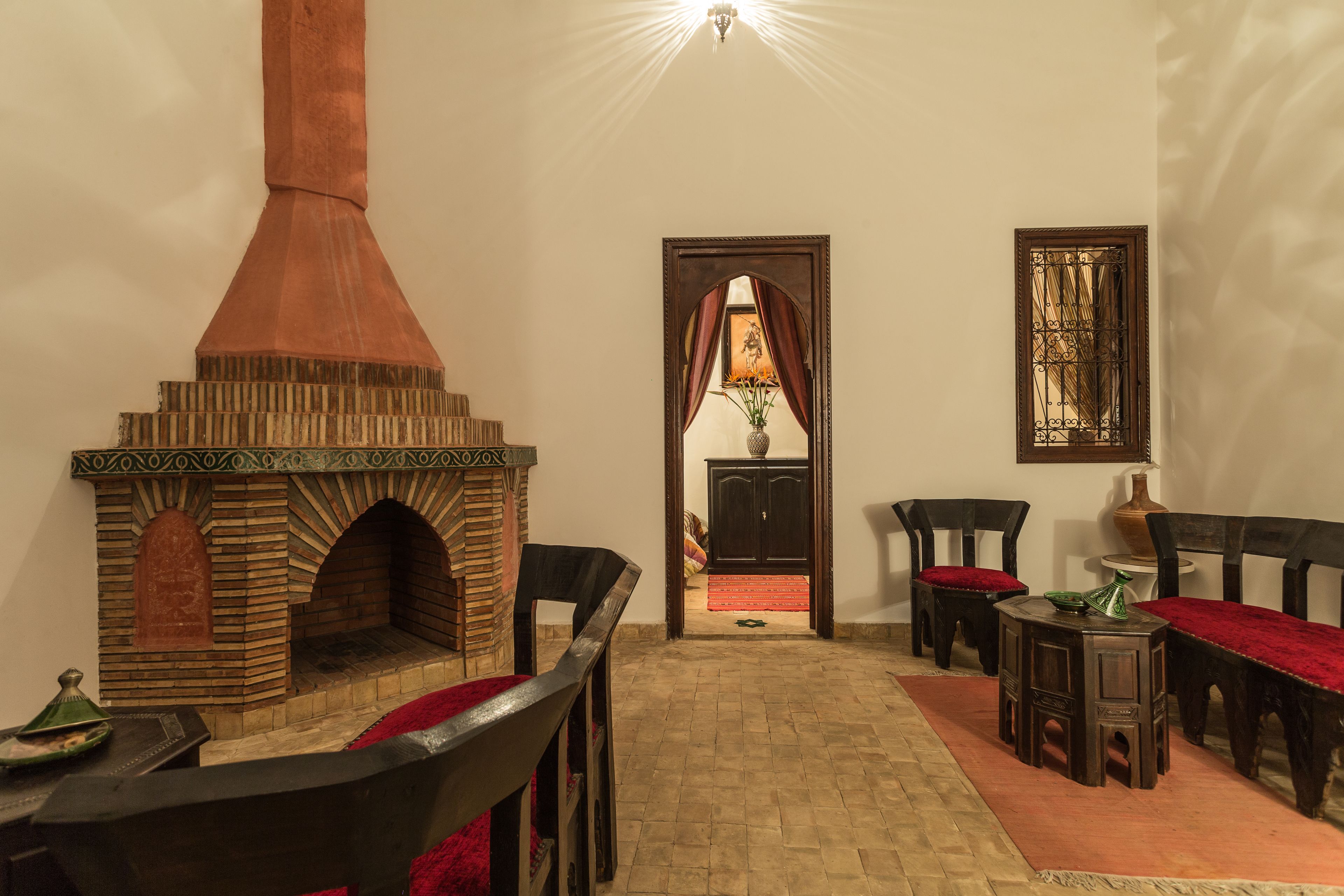 A traditional room with a brick oven, wooden furniture, and a view of a door leading to another room.