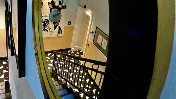 A spiral staircase with a geometric patterned floor and a black railing. - Hotel AVAlex (Berlin)