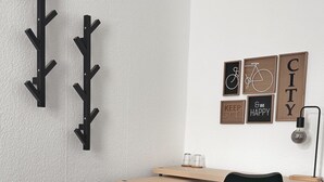 A room with a bed, a desk, a chair, a wall-mounted coat rack, and motivational posters. - Hotel AVAlex (Berlin)