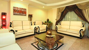 A living room with two cream sofas, a coffee table, a painting, and a lamp.