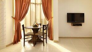 A dining area with a round table, two chairs, and a TV mounted on the wall.