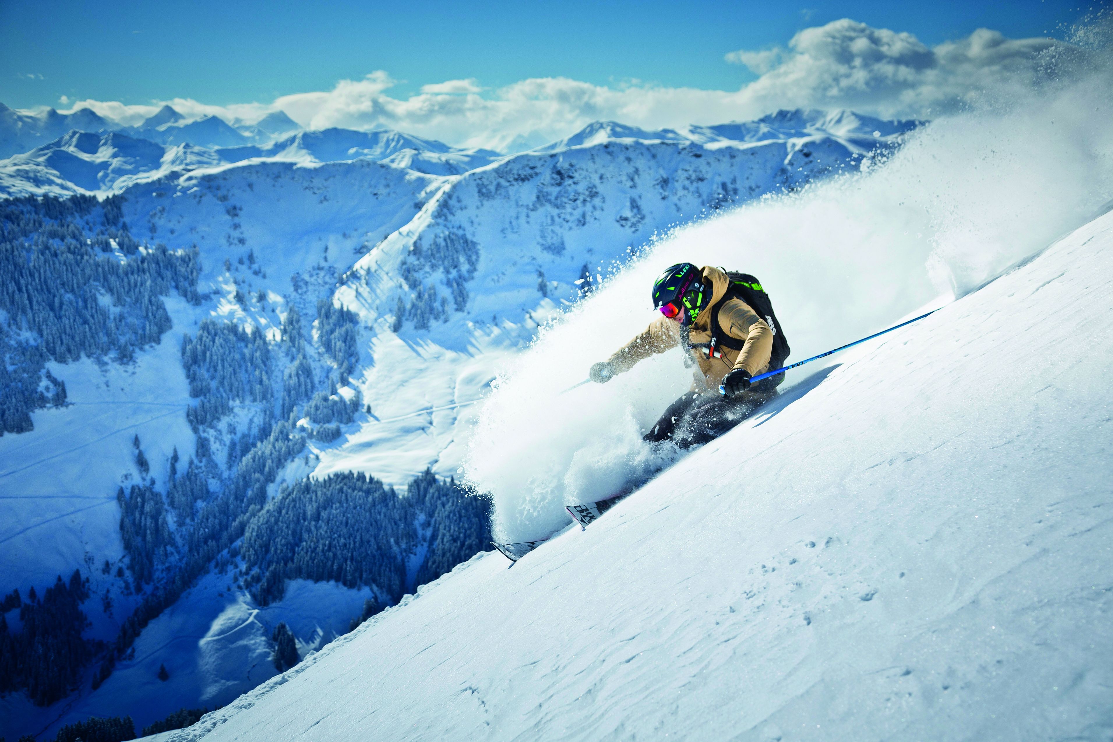 A skier on a snowy slope with a mountainous backdrop.