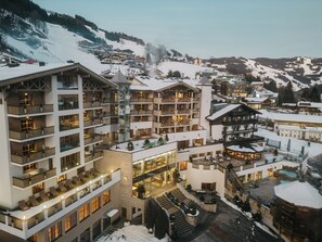 A multi-story hotel with balconies, a central courtyard, and a ski resort in the background. - Hotel Alpine Palace (Saalbach-Hinterglemm)