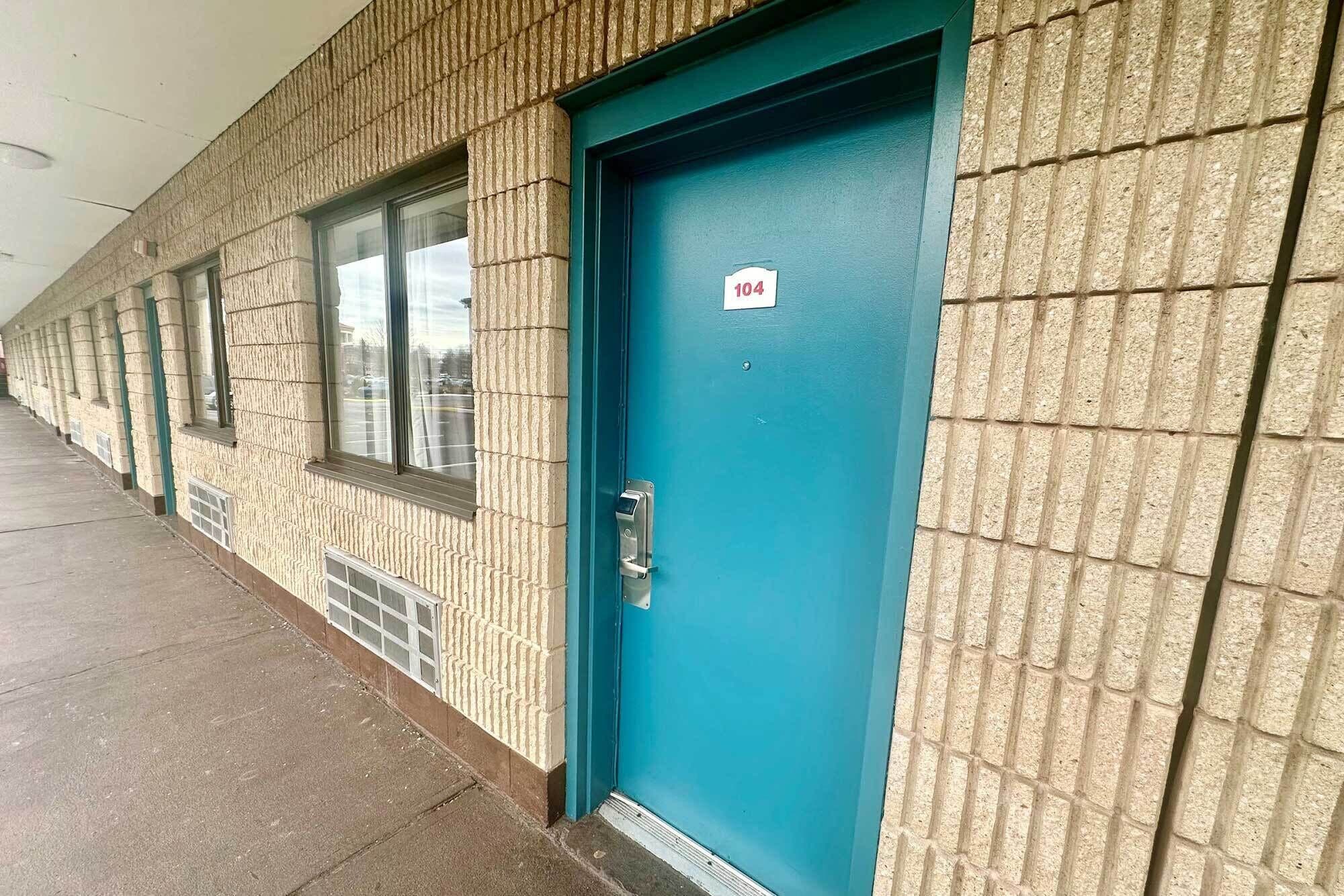 Un edificio con una puerta azul numerada 104, una ventana y un muro con textura.