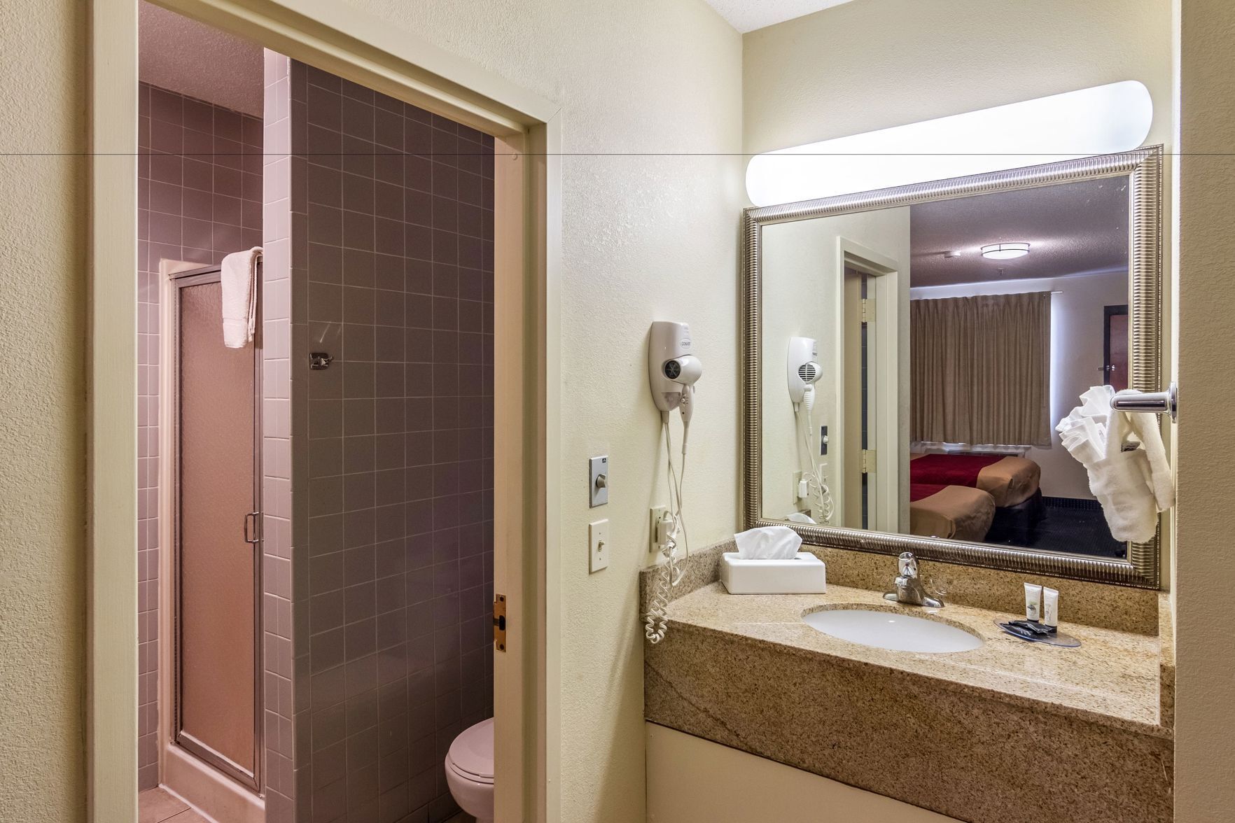 A bathroom with a shower, toilet, sink, and a mirror.