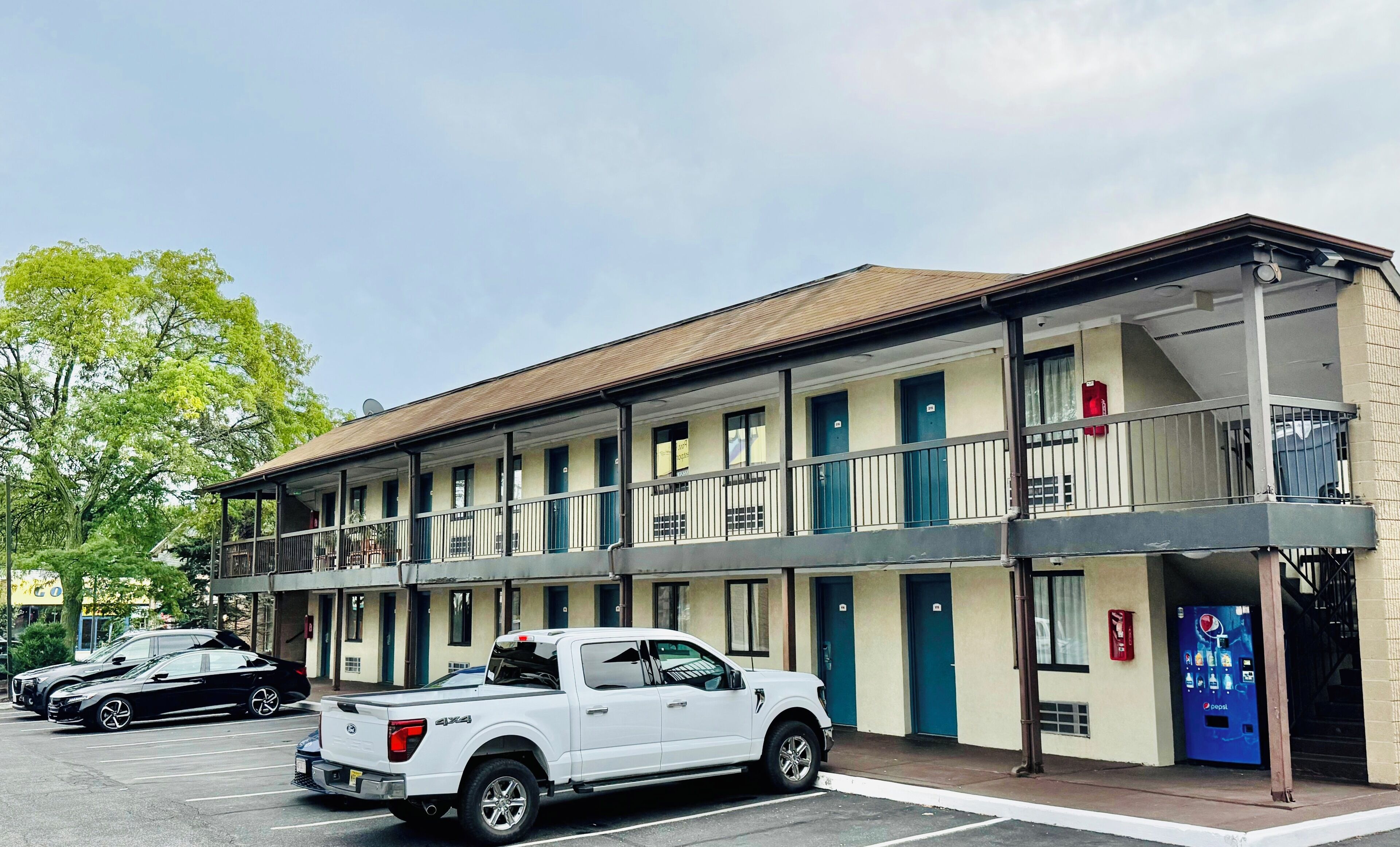A motel with a two-story structure, a covered parking area, and a Pepsi vending machine.