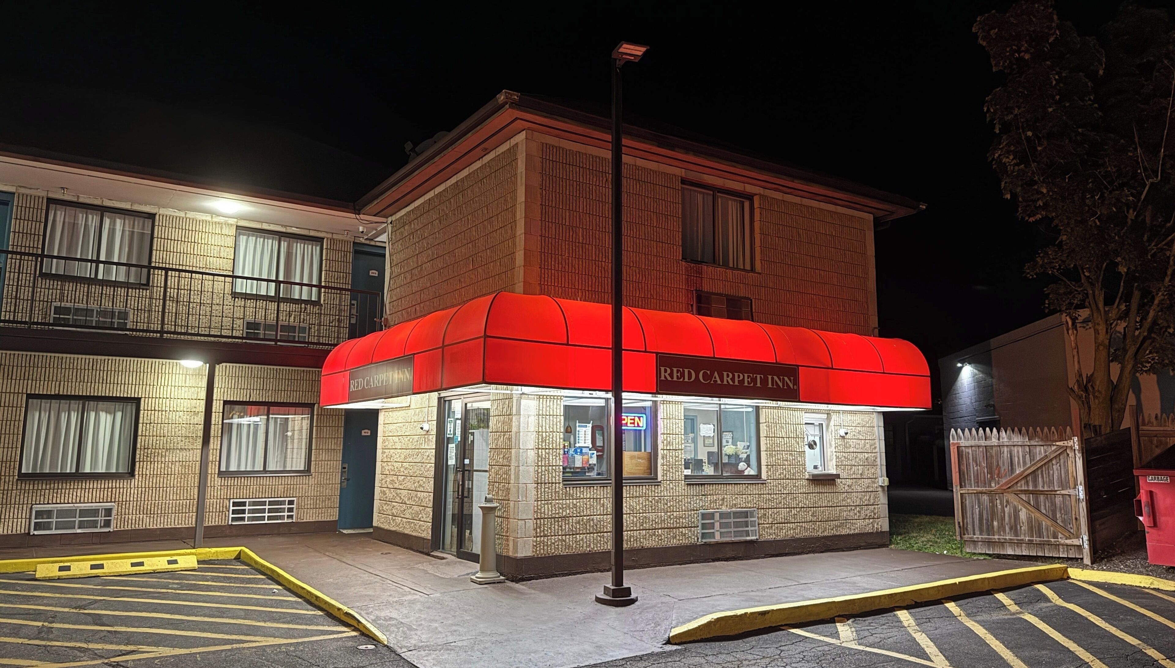 En toetagers bygning med en rød markise med teksten "Red Carpet Inn".