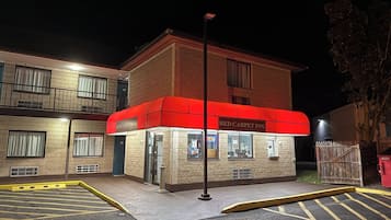 En toetagers bygning med en rød markise med teksten "Red Carpet Inn".