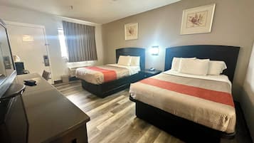 Habitación de hotel con dos camas, un escritorio y una silla.