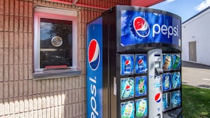 Ein Getränkeautomat mit Pepsi-Logo, vor einem Gebäude mit Backsteinfassade.