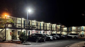 Ein mehrstöckiges Hotel mit einer Reihe geparkter Autos davor.