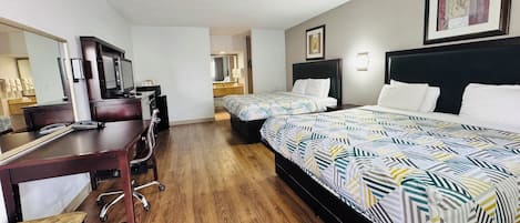 A hotel room with two beds, a desk with a chair, a TV, and a large mirror.