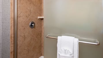 A bathroom with a shower, a towel rack, and a toilet paper holder.