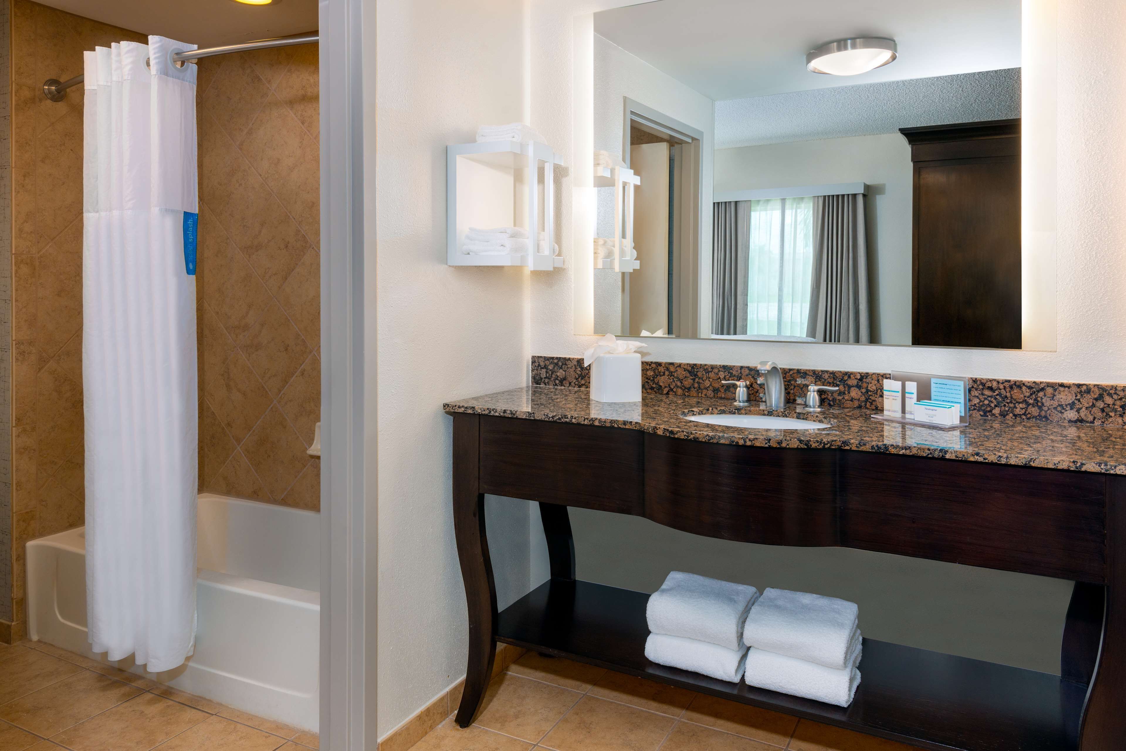 A bathroom with a bathtub, a vanity with a sink, a mirror, and a towel rack.