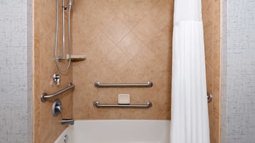 A bathroom with a bathtub, a shower, and grab bars.