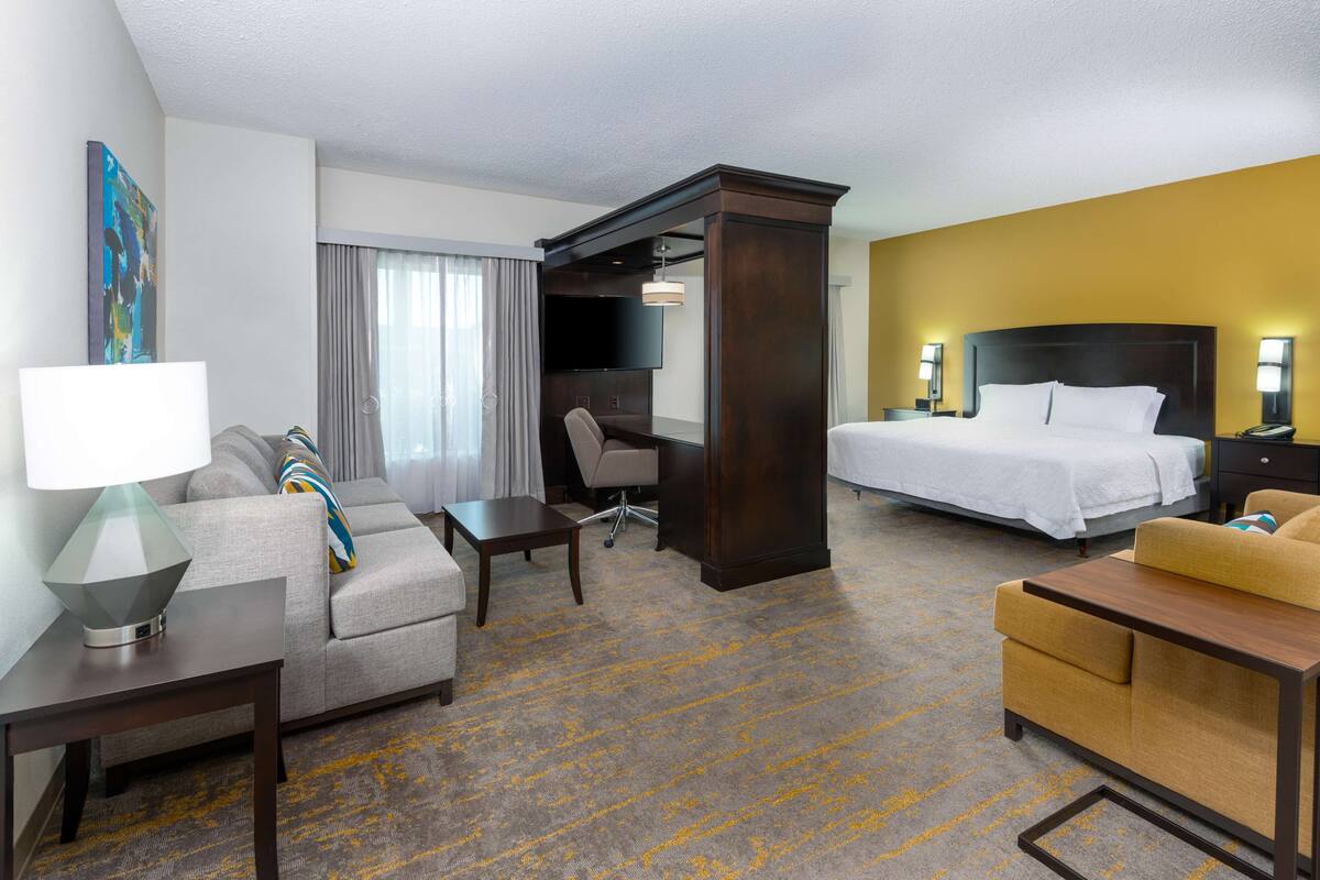 A hotel room with a bed, a sofa, a desk, and a TV.