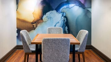 Een eethoek met een houten tafel en vier grijze fauteuils.