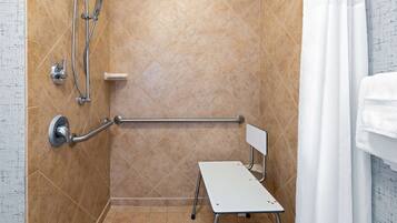 A shower area with a grab bar, a handheld showerhead, and a towel rack.