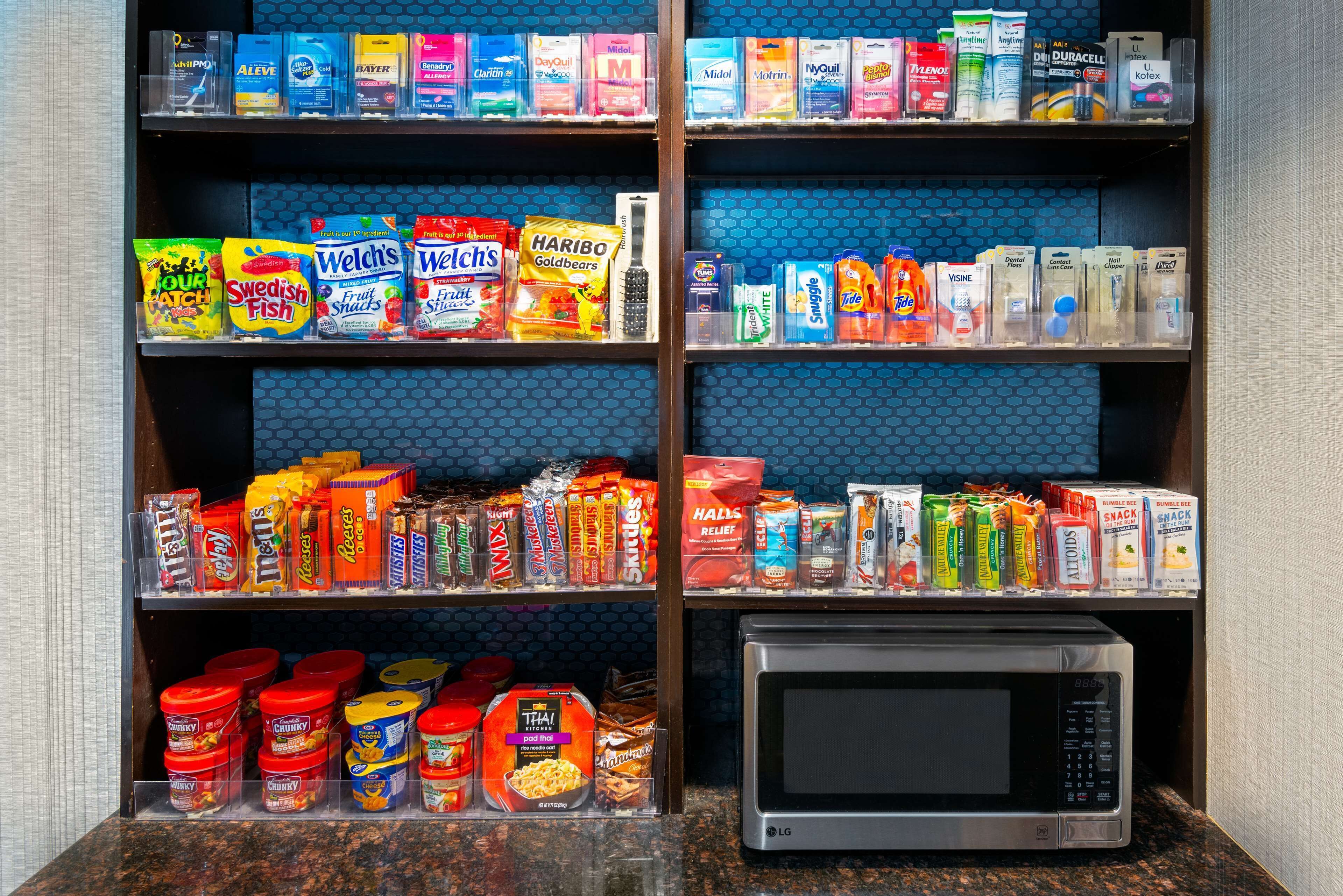 A shelf stocked with various food items and a microwave.